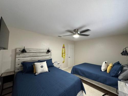 a bedroom with two beds and a ceiling fan at Three Treasures Beach House in New Smyrna Beach
