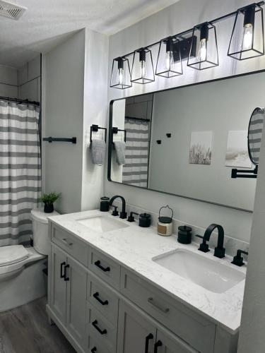 a bathroom with two sinks and a mirror and a toilet at Three Treasures Beach House in New Smyrna Beach