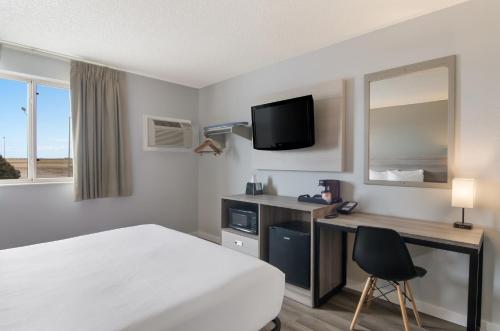 a hotel room with a bed and a desk and a tv at Econo Lodge Scottsbluff in Scottsbluff