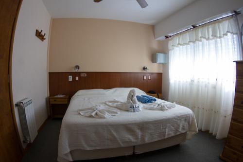 un dormitorio con cama con toallas en el Hotel Teomar de Villa Gesell