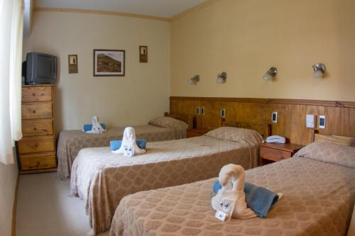 a hotel room with three beds with dolls on them at Hotel Teomar in Villa Gesell