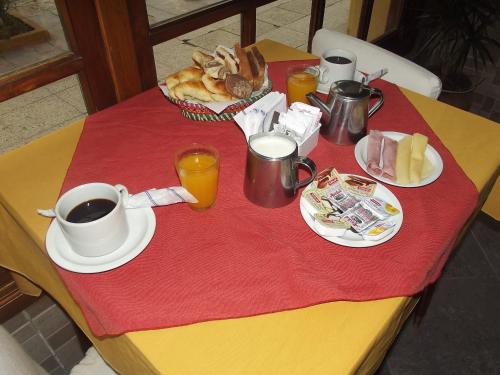 a table with a breakfast of coffee and pastries on it at Hotel Teomar in Villa Gesell