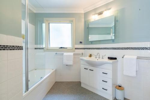 y baño blanco con lavamanos y ducha. en Tall Trees- Forest hideaway on Hastings Lagoon, en Hastings