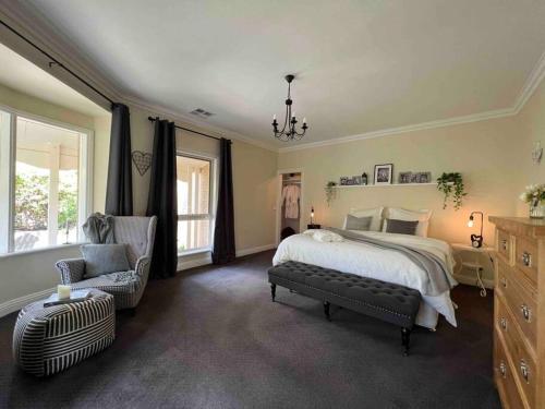a large bedroom with a bed and a chair at Cosy Country Cottage in Neerim South