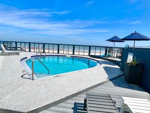 a swimming pool on a deck next to the ocean at Beach Daze - Ocean front at Symphony Beach Club! in Ormond Beach