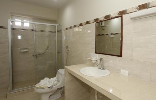 a bathroom with a shower and a sink and a toilet at La Costa Playa El Agua Hotel in El Agua