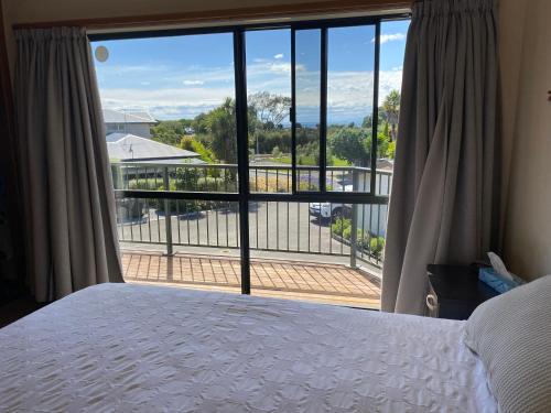a bedroom with a bed and a view of a balcony at Unit 12 Kaiteri Apartments and Holiday Homes in Kaiteriteri