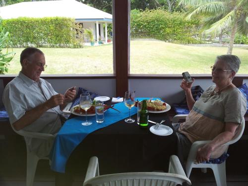 twee oudere mensen aan een tafel eten bij Island Magic Resort Apartments in Port Vila
