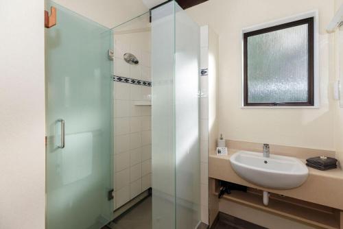a bathroom with a sink and a glass shower at Unit 4 Kaiteri Apartments and Holiday Homes in Kaiteriteri
