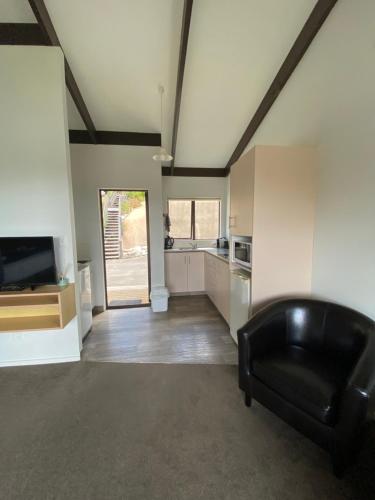 a living room with a black couch and a kitchen at Unit 4 Kaiteri Apartments and Holiday Homes in Kaiteriteri