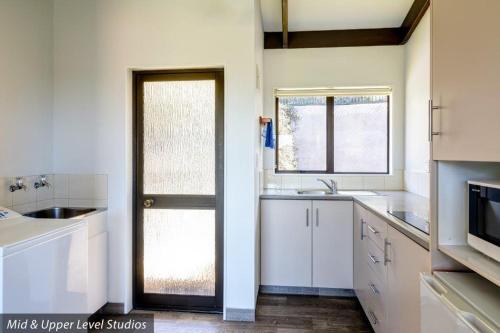 a kitchen with white cabinets and a door with a window at Unit 6 Kaiteri Apartments and Holiday Homes in Kaiteriteri