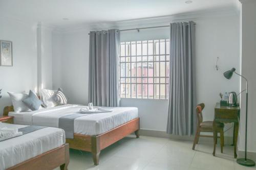 a bedroom with a bed and a desk and a window at White Corner Hotel in Phnom Penh