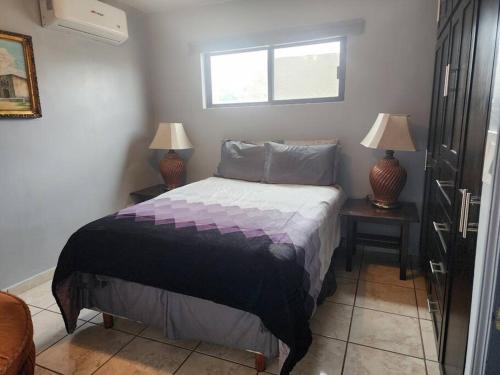 a bedroom with a bed with two lamps and a window at Apartment Downtown Cananea in Cananea