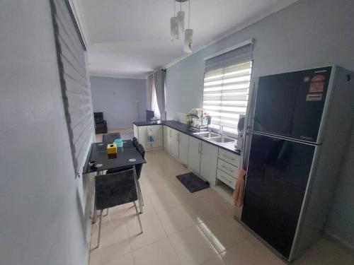 a kitchen with a black refrigerator and a table at My Pool House in Alor Setar