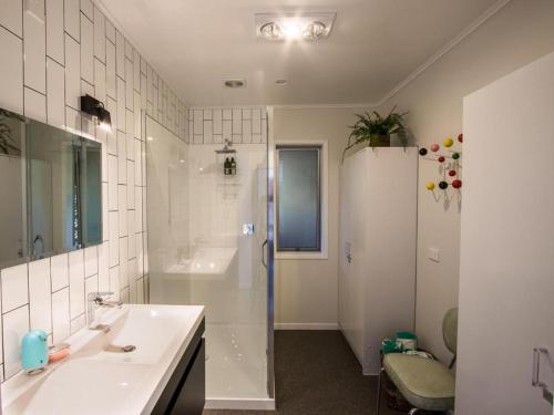 a white bathroom with a sink and a shower at Mon Coeur Holiday Home in Kaiteriteri