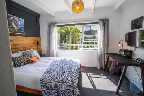 a bedroom with a bed and a desk and a window at Mon Coeur Holiday Home in Kaiteriteri