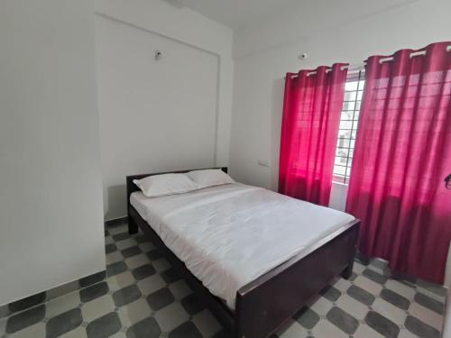 a bedroom with a bed and red curtains at Navilu Homes in Mysore