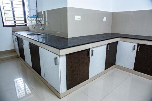 uma cozinha com um balcão preto e branco em Ecoville suites em Calecute