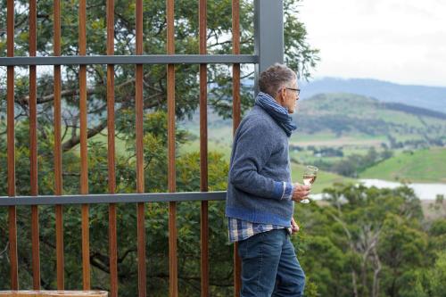 a man is standing next to a fence holding a drink at Aquila Eco Retreat in Richmond