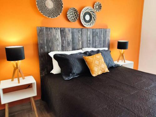 a bedroom with a black bed with an orange wall at Hermosa casa para conocer León in León