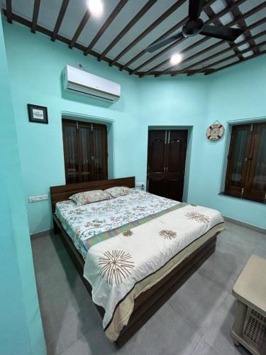 a bedroom with a large bed with blue walls at Teakwood Suite - Nokha House in Kolkata