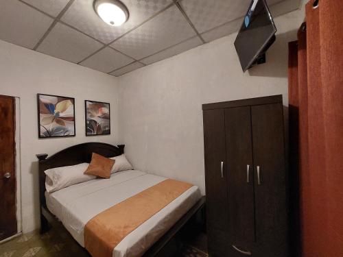 a bedroom with a bed and a cabinet and a television at Hospedaje Los Lirios Chitré in Chitré