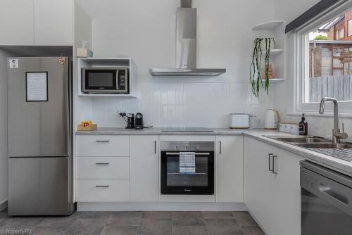 a white kitchen with a refrigerator and a microwave at Bella Vista on Beach in Hobart