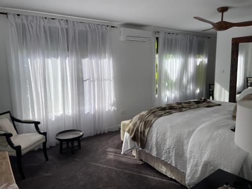 a bedroom with a bed and a chair and windows at Jetty beach shack in Coffs Harbour