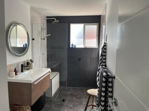a bathroom with a shower and a sink and a mirror at Jetty beach shack in Coffs Harbour