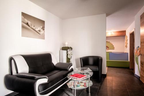 a living room with a black couch and a glass table at Haus Buchhammer in Fiss