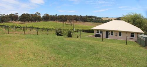 a small white house in a field of green grass at Hill Cottage Hahndorf in Hahndorf