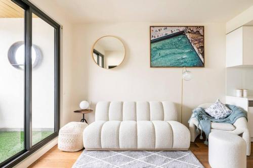 a living room with a white couch and a mirror at Beachside flat with free parking in Melbourne