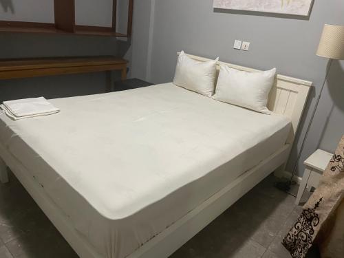 a bed with white sheets and pillows in a room at The Gulch in Douala