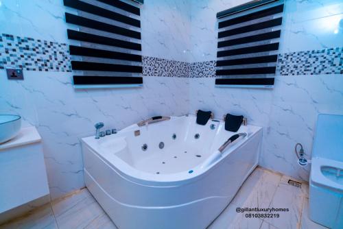 a white tub in a bathroom with black and white tiles at Gillant Luxury Homes in Benin City