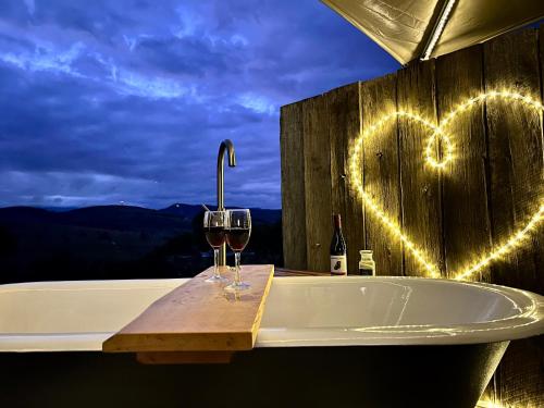 a bath tub with wine glasses and a heart drawn on the wall at Aquila Eco Retreat in Richmond