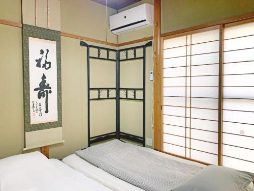 a bedroom with a bed in a room with a window at 花楓舎-Sakura & Maple Guest House-ゲストハウス in Kyoto