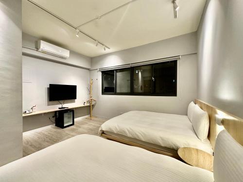 1 dormitorio con 2 camas y TV de pantalla plana en 茗居 House, en Taichung