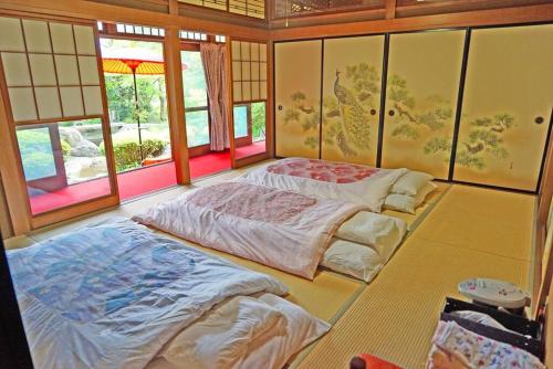 two beds sitting in a room with windows at 日本庭園古民家　飯田屋　Traditional experience iidayajapan in Yokohama