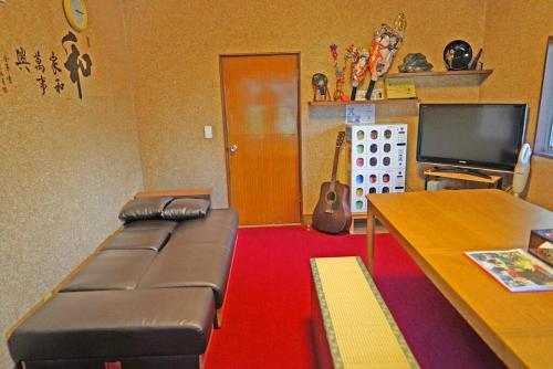 a living room with a leather couch and a television at 日本庭園古民家　飯田屋　Traditional experience iidayajapan in Yokohama
