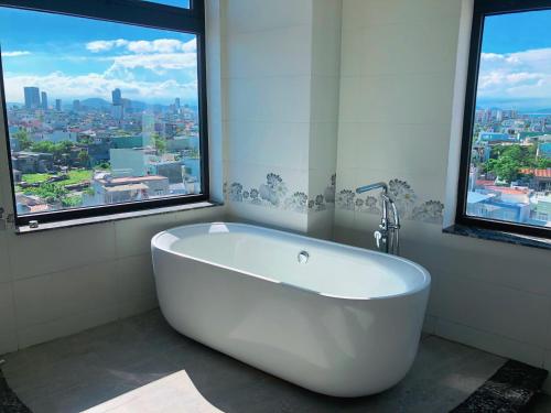 a white bath tub in a bathroom with windows at Mercury Beach DaNang in Danang
