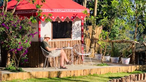 a woman sitting in a chair in front of a house at Hoàng Gia Trang in Da Lat