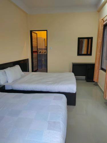 Kavre Guest House في لومبيني: غرفة نوم بسريرين ونافذة ومرآة