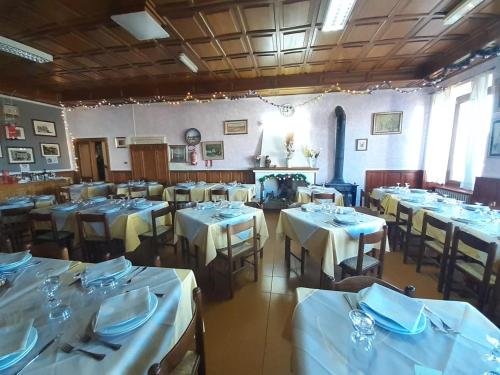 een eetkamer met tafels en stoelen met witte tafelkleden bij Hotel Moderno in Aritzo