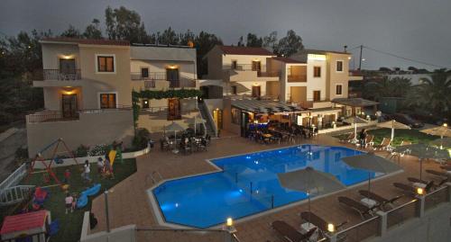 a building with a swimming pool in front of a house at Asterion Apartments in Panormos Rethymno