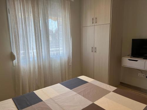 a bedroom with a bed and a tv and a window at CASA MILITOU-NEA FILADELFIA in Athens