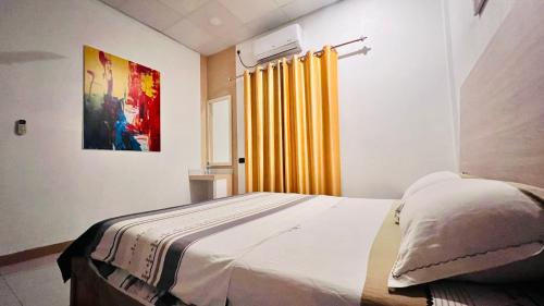a bedroom with a bed and a yellow curtain at Muladdu Inn in Feydhoo