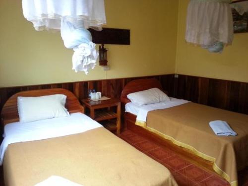 Zimmer mit 2 Betten und einem Fenster mit Vorhängen in der Unterkunft Pon's Riverside Guesthouse in Muang Không