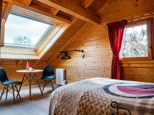 a bedroom with a bed and two chairs and a table at Le Chalet au vieux vignoble avec espace Sauna et Jacuzzi in Bouxwiller