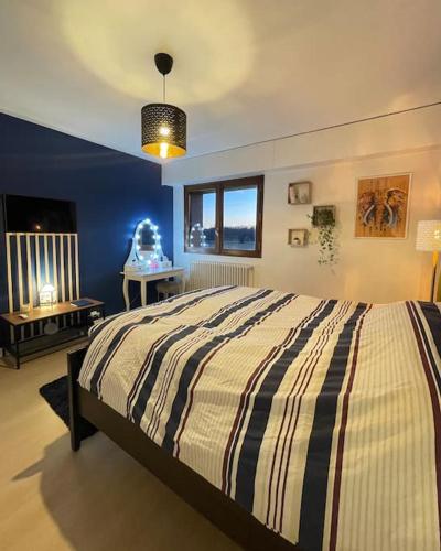 una camera da letto con un letto con un piumone a righe di Appartement Très Cosy à 5 min Aéroport Genève a Ferney-Voltaire