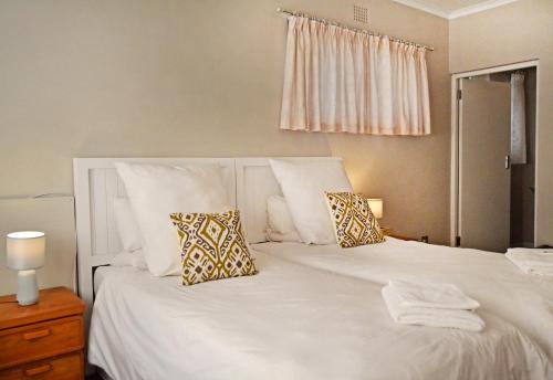 a bedroom with a white bed with two pillows at Chesham House in Hermanus